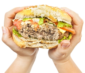 Hands holding a partially eaten hamburger