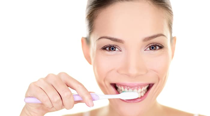 Woman brushing teeth holding toothbrush