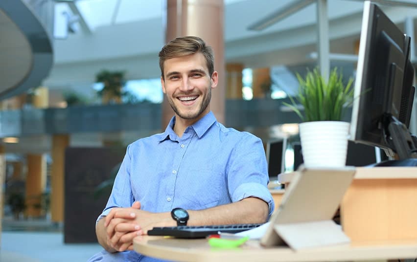 Career minded man working on his computer at work. Due to numerous things like coffee and cigarettes he no longer liked his teeth. Now with the help of the dentists in Tarrytown he's improved his oral health.