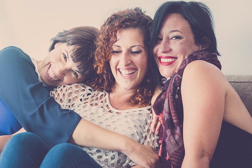 3 middle aged woman enjoy a laugh with one another as they share a smile. 3 best friends learning the 3 benefits of porcelain veneers.