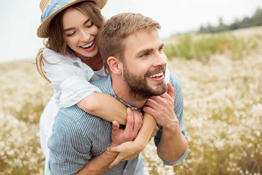 A young couple in love spends like in a field with one another. TMJ can cause so much pain, preventing you from living your life. With a bite splint, our Tarrytown Dentists can offer you relief.
