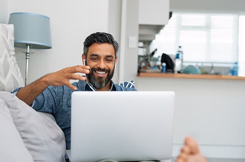 man sitting in front of this laptop while sitting on the couch