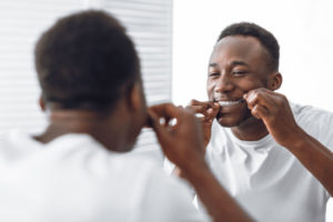 a dental implant patient flossing his teeth