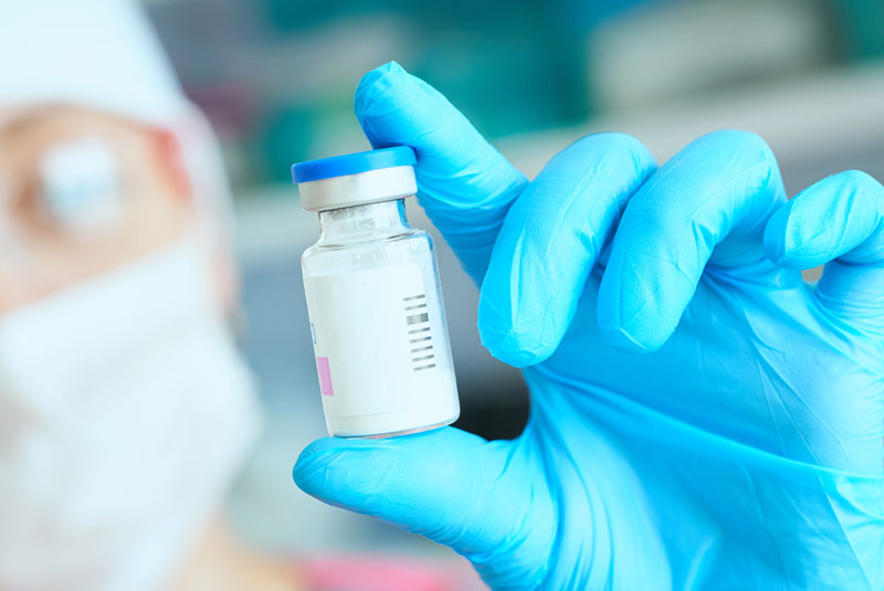 A picture of a dentists hand holding a local anesthetic bottle